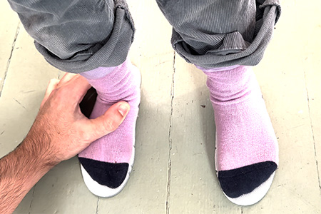 A child standing on a pair of shoe insoles to check if there is growing room inside her shoes.