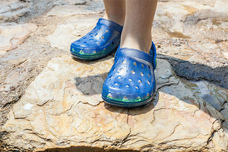 Child wearing blue Crocs.