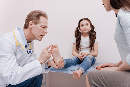 A medical professional helping a child with toe pain.