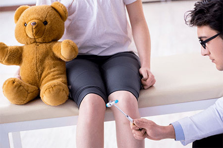 Medical professional diagnosing a child with knee pain.
