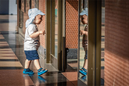 Toddler learning how to walk wearing a pair of first walking shoes.