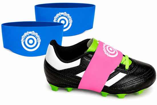 Black youth soccer cleat fitted with a pink Lace Bandz strap alongside two blue Lace Bandz silicone bands on a white background.